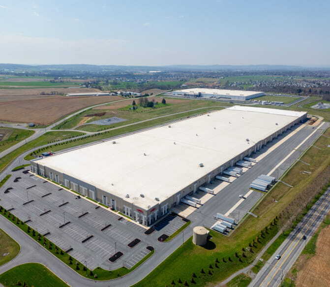 Aerial view of a large warehouse distribution center with trucks at loading docks